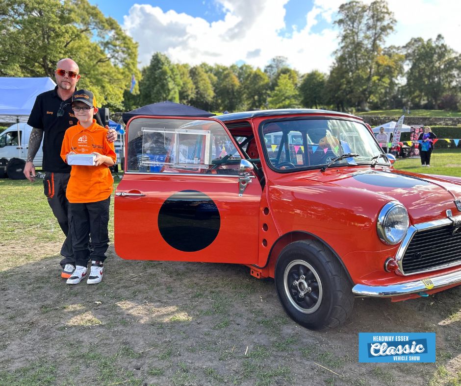 Image shows orange vintage mini with father and son who are holding up a winners trophy